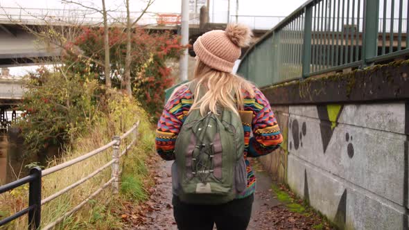 woman walking on a little path inbetween the roads and the river in Bristol Uk.