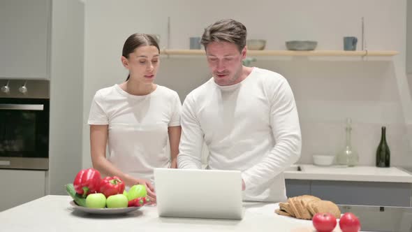 Mixed Race Couple Working on Laptop in Kitchen