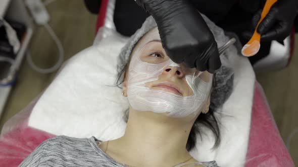 Cosmetologist Applying Moisturizing Cream Mask Using Brush on Woman Client Face