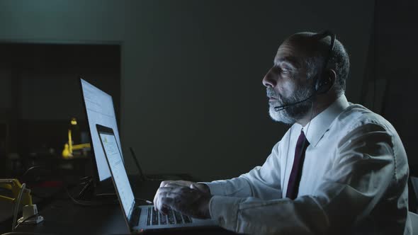 Focused Man in Headset Using Laptop