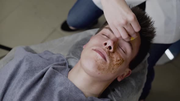 Top View of Beautician's Hands Clean Male Face with Sponge From a Coffee Scrub