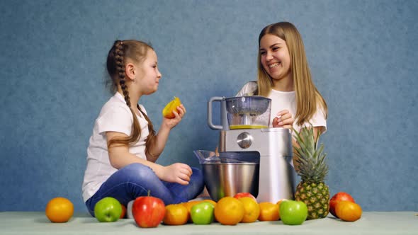 Mother and daughter making juice from fresh fruits