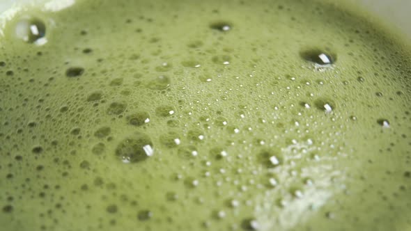 Frothed matcha green tea. The froth rotates with bubbles