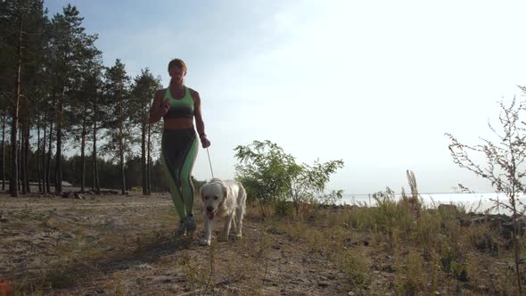 Fit Female Running Along Shore with Labrador Pet