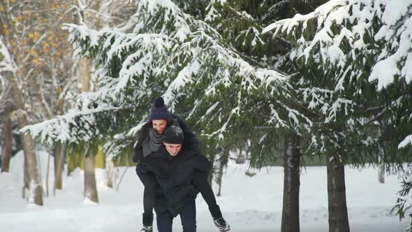 Woman Riding Man in Winter Park