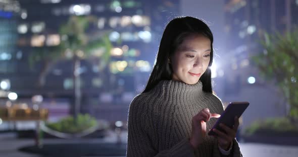 Woman working on smart phone at night