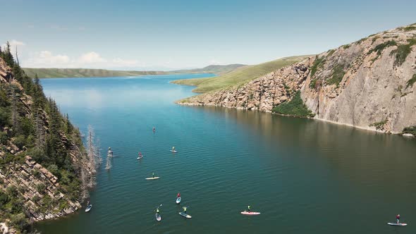 People Ride on SUP Board in the Mountain Lake