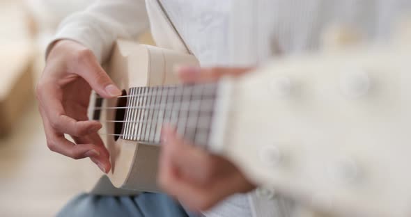 Woman play ukulele at home