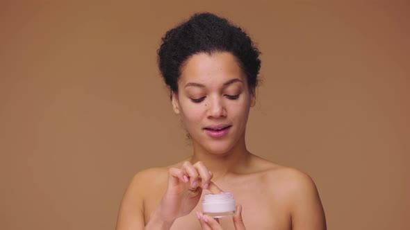 Beauty Portrait of Young African American Woman Who Take Face Cream Her Finger