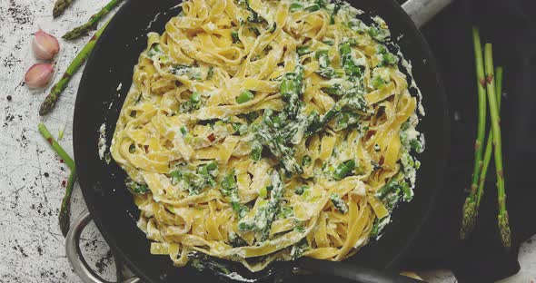 Tagliatelle Pasta with Ricotta Cheese Sauce and Asparagus Served on a Black Iron Pan