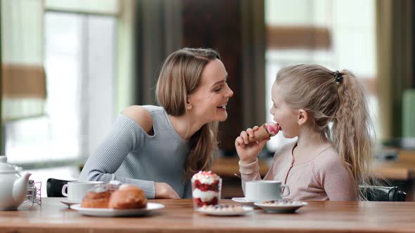Happy Mother and Daughter Eat Dessert Together at Cafe Having Fun