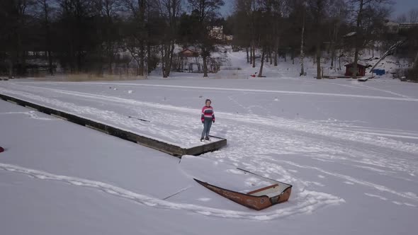 Low angle dolly shot rotating around lonely girl staring over the infinite vastness of a frozen lake