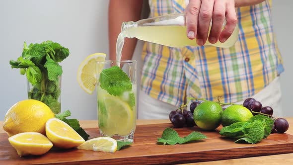 Cinemagraph, pouring lemonade from a bottle into glass with mint, ice cubes and lemon slices