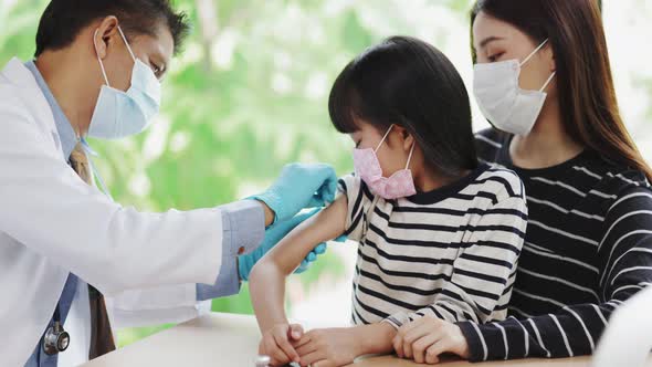 Asian  senior doctor wearing gloves and isolation mask is making a COVID-19 vaccination