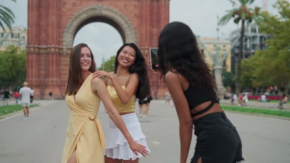 Three Young Overjoyed Multiracial Women Friends Having Fun and Photographing Near Famous Landmark