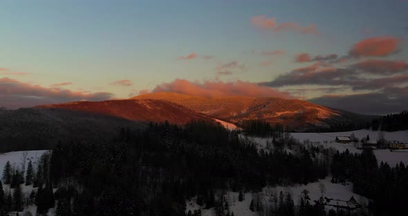 Aerial View of Mountains and Forest Covered with Snow at Sunset in Winter