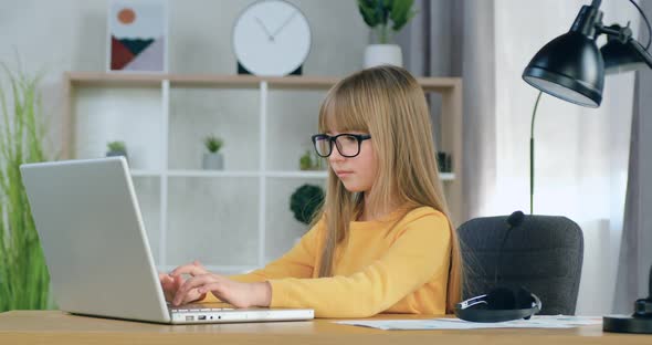 Girl in Glasses which Sitting in front of Computer and Honestly Doing Her Homework
