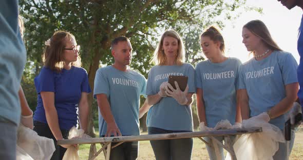 Mid adults volunteering and woman taking notes during river clean-up day