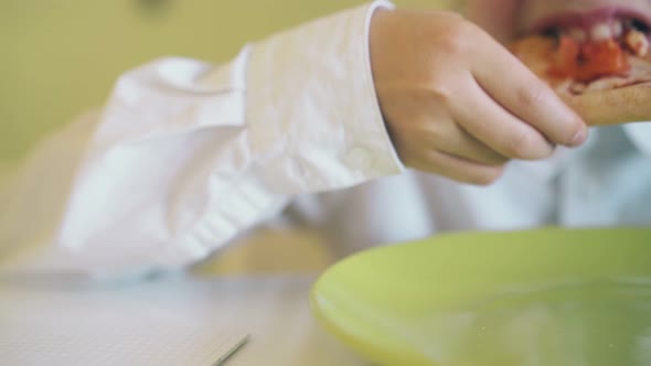 Cute Boy Eats Piece of Pizza From Plate at Table Slow Motion