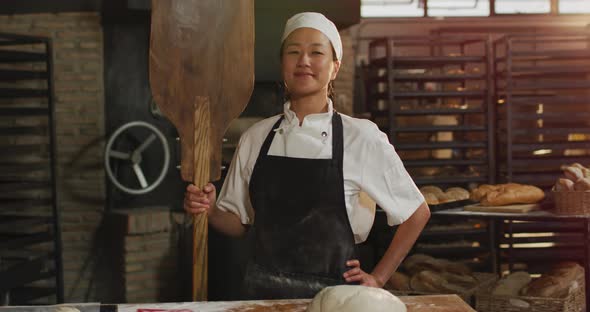 Animation of happy asian female baker holding wooden spatula