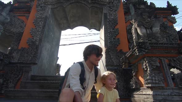 Slowmotion Shot of a Father and Son Tourists Sitting on the Stairs of a Balinese Temple