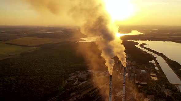 Industrial zone with pipes among nature. Thick white smoke is poured from the factory pipe 