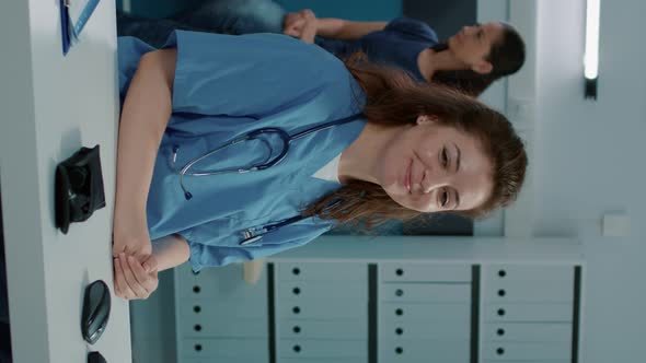 Vertical Video Portrait of Woman Nurse Sitting at Desk in Doctors Office