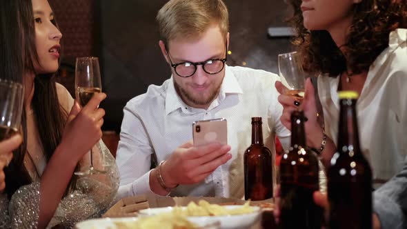 Friends in a Pub Celebrate and Have Fun, One Guy Is Looking at a Smartphone, and Not Talking To