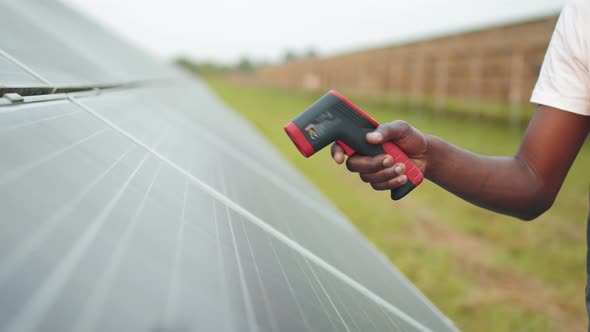 Close Up of Male Hand Holding Electronic Thermal Imager Near Solar Cell Outdoors