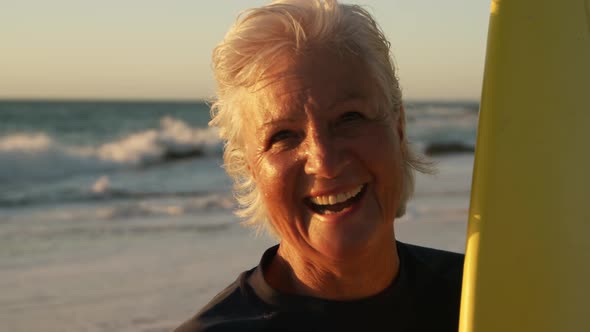 Senior woman with a surfboard smiling