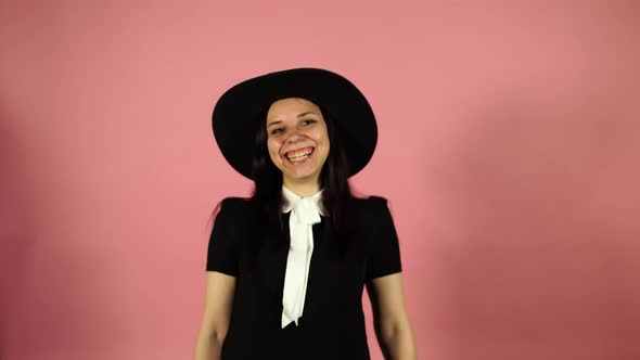 Lady Smiling on a Pink Background. A Woman in a Black Dress and a Hat.