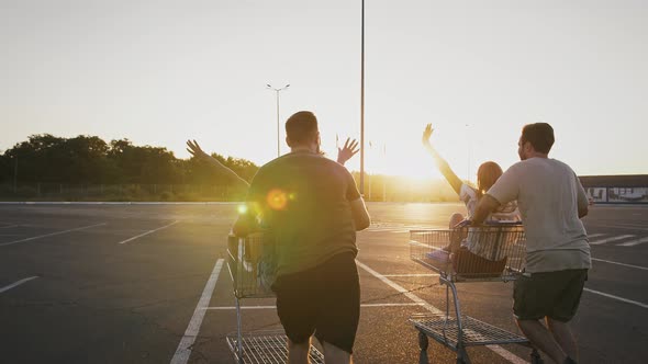 Young Males are Racing Shopping Trolleys with Their Girlfriends at Deserted Parking Lot of