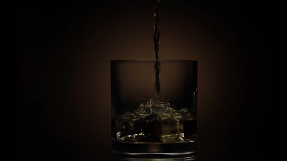 Pouring Whiskey, Cognac Into Glass. Dark Background. Pour of Alcohol Drink