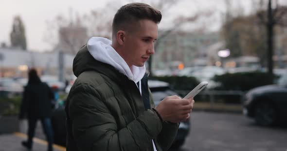 Portrait of Man Using Smartphone in the City and Looks Forward