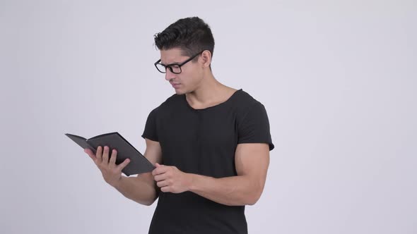 Happy Young Handsome Multi-ethnic Nerd Man Reading Book