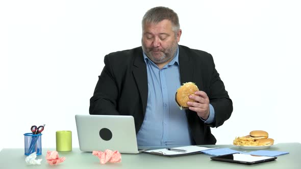 Businessman Works at a Computer and Eats Fast Food