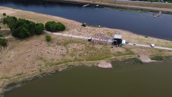 Music festival in two river conjunction with crowd of people, aerial drone view