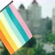 Flag of the LGBTQ set against blue sky and city street. Rainbow stripes on colorful LGBT flag - VideoHive Item for Sale