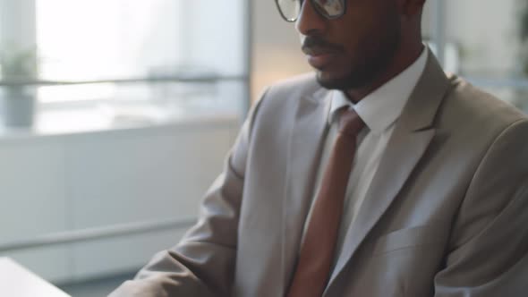 Black Businessman Typing on Laptop at Office Desk