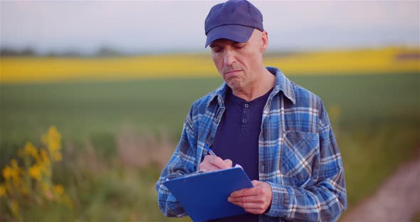 Thoughtful Male Botanist Writing On Clipboard