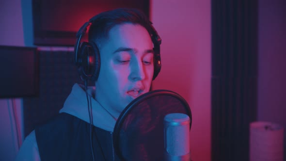 A Man Rapping Through the Pop-filter in the Microphone - Neon Lighting
