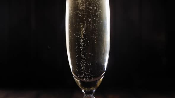 Closeup of a Glass of Champagne with Bubbles on a Black Background Slow Motion