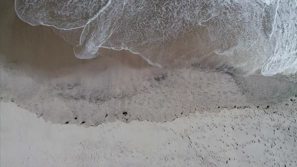 Top View and Vertical Pan of Waves Crashing on the Beach Shore
