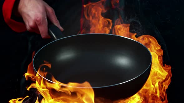 Super Slow Motion Shot of Chef Holding Empty Frying Pan and Flames at 1000Fps.