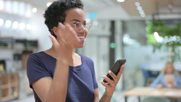 Portrait of Casual African Woman Celebrating Success on Smartphone