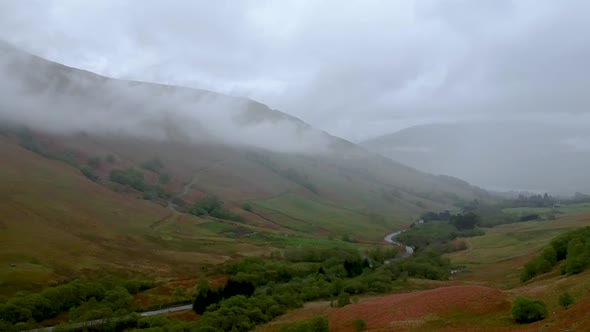 Cinematic drone shot of scottish highlands landcsape with winding road