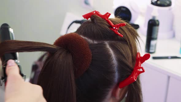 The Hairdresser's Hands Curl the Hair on the Girl's Head with Hot Tongs