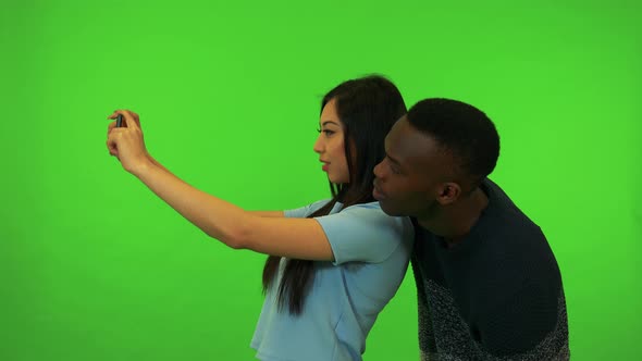 A Young Asian Woman and a Young Black Man Take Pictures of Their Surroundings - Green Screen Studio