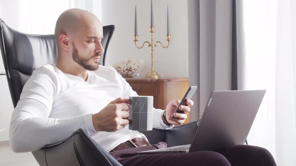 Bearded businessman working at home sitting in armchair. Business and investments concepts.