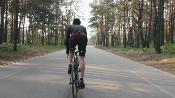 Cyclist with strong leg muscles pedaling on bicycle in the park